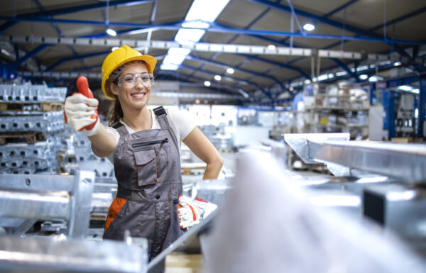 Portrait of female factory worker holding thumbs up.